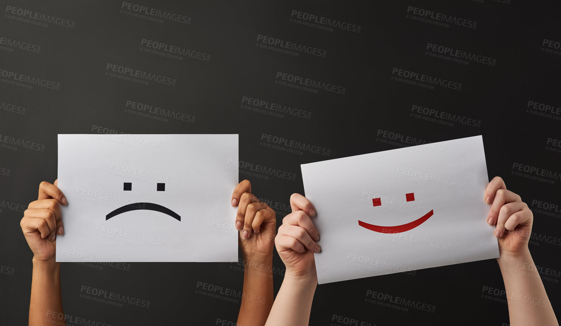 Buy stock photo Shot of two people holding a sign with happy and sad smileys on against a dark background