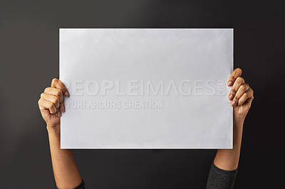Buy stock photo Shot of a person holding up a blank page against a dark background