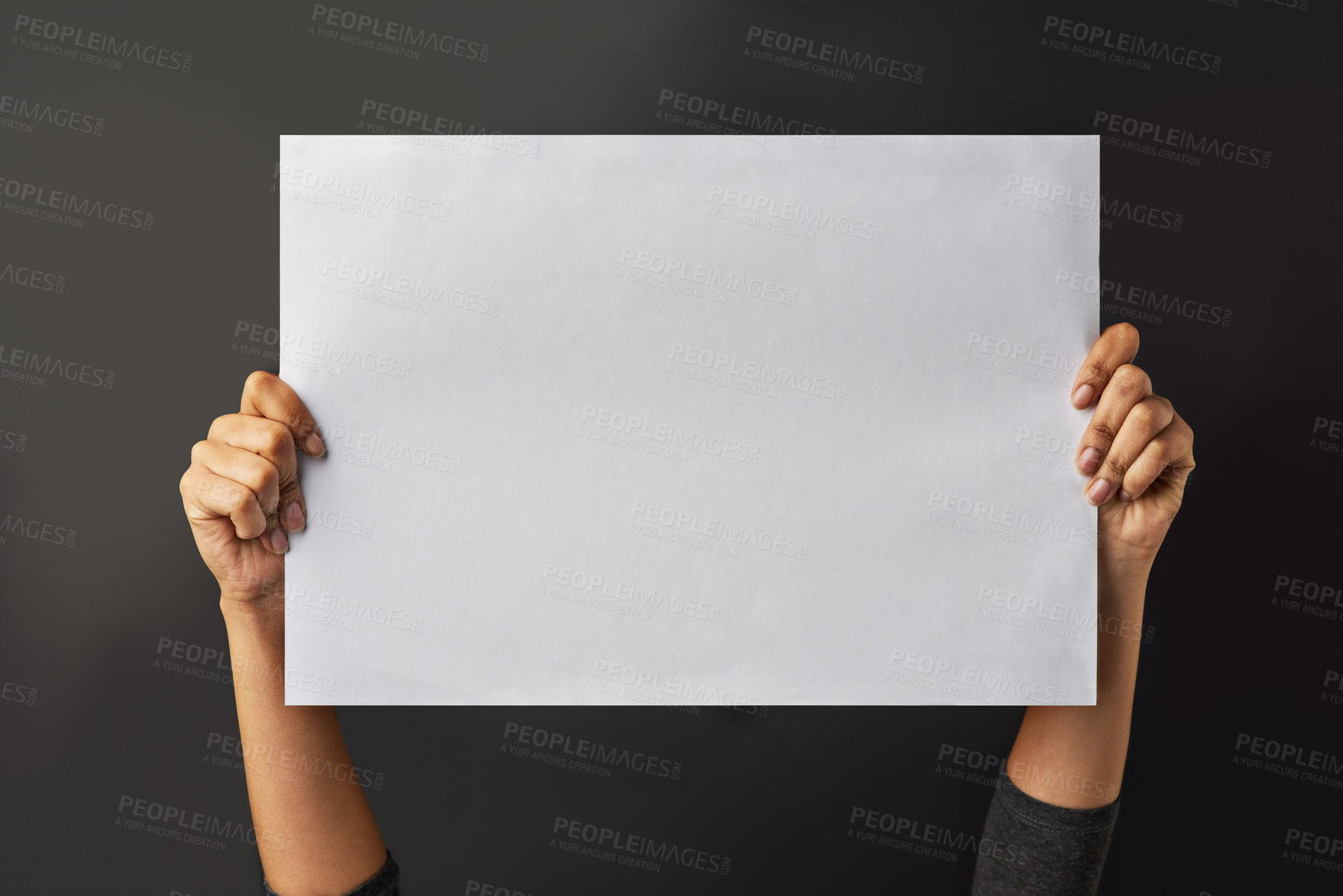 Buy stock photo Shot of a person holding up a blank page against a dark background