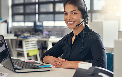 Buy stock photo Shot of a call centre agent sitting at her desk in a modern office