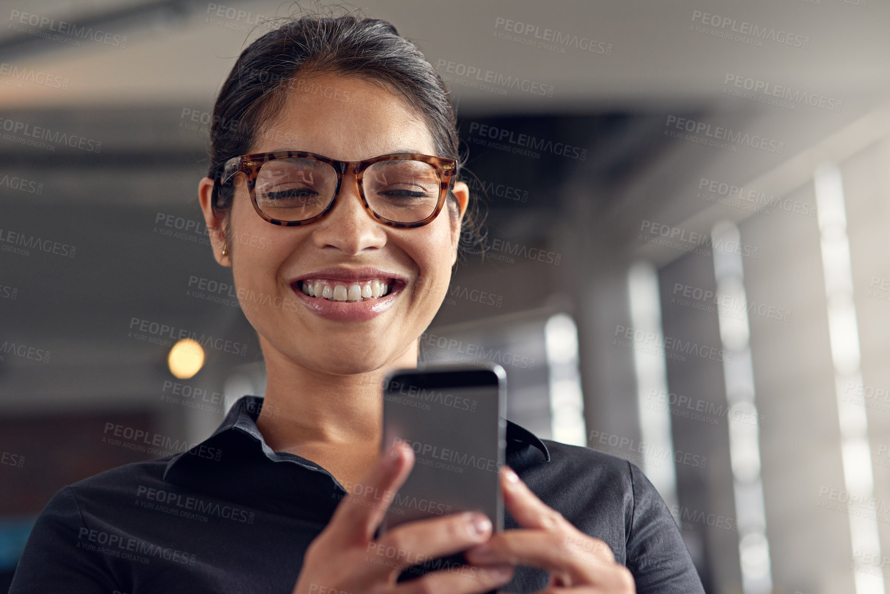 Buy stock photo Shot of a young businesswoman using her cellphone at the office