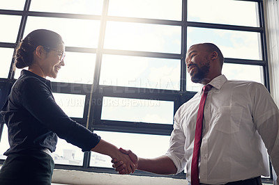 Buy stock photo Shot of two businesspeople shaking hands in an office