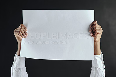 Buy stock photo Shot of hands holding up a blank page against a dark background