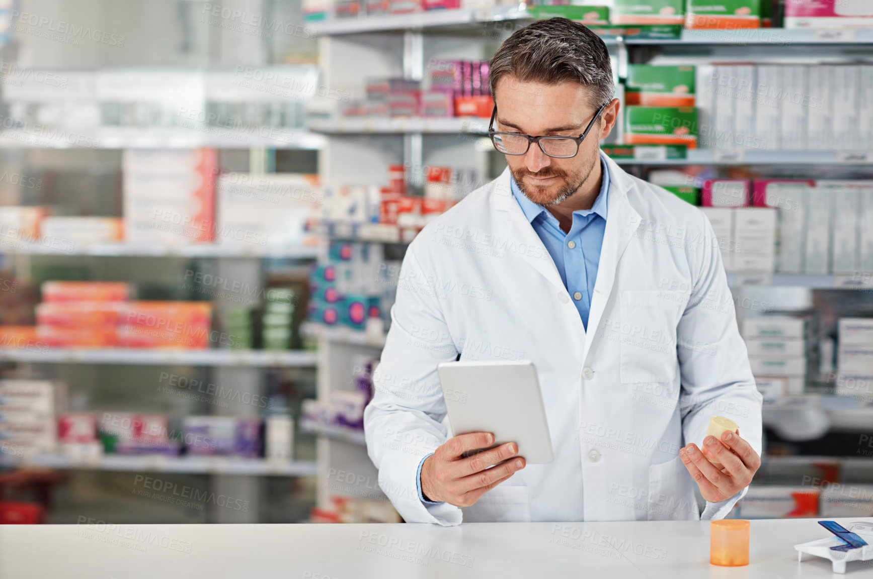 Buy stock photo Pharmacist man, shop and reading with tablet, medicine, pills and counter for health, medication or sales. Medical professional, pharma expert and mobile digital tech in pharmacy with wellness app