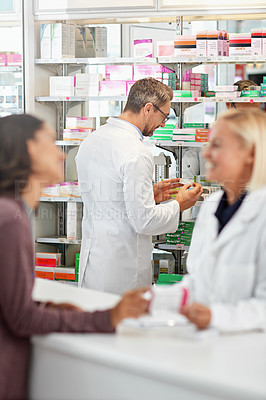 Buy stock photo Shot of pharmacists helping a customer in a pharmacy. All products have been altered to be void of copyright infringements