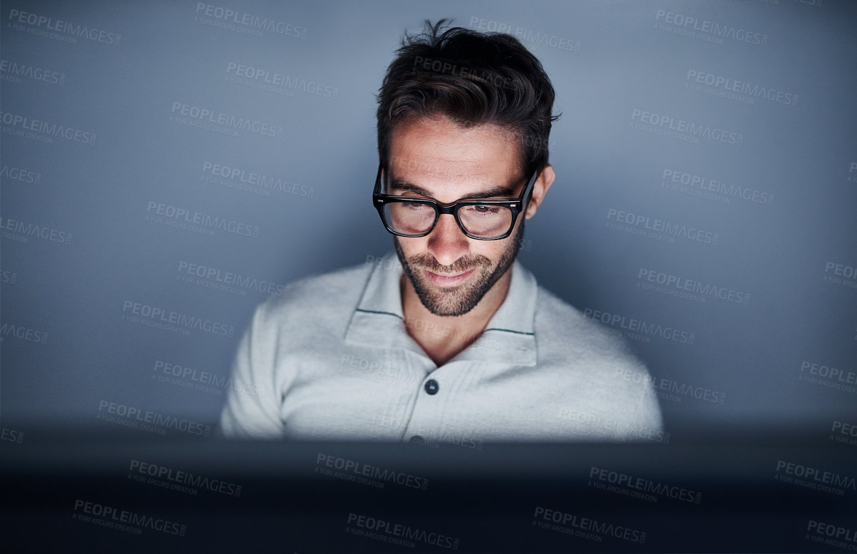 Buy stock photo Shot of a handsome young man working late on a computer