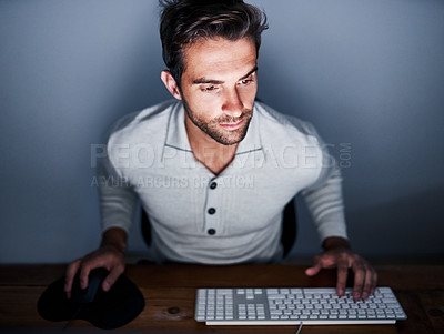 Buy stock photo Shot of a handsome young man working late on a computer