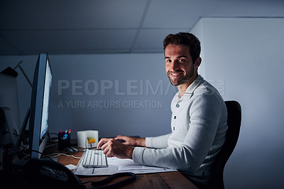 Buy stock photo Portrait of a handsome young man working late on a computer