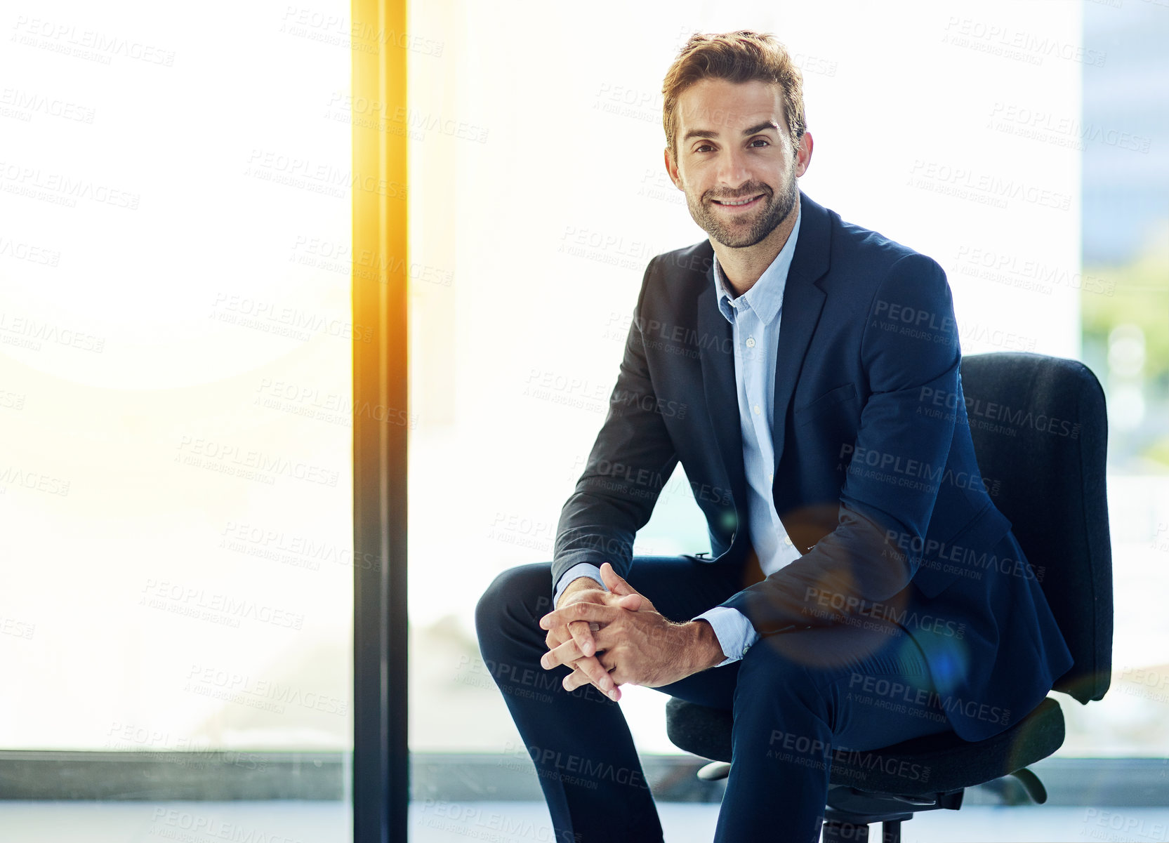 Buy stock photo Portrait, confident and business man sitting in chair for career pride, smiling or happiness in office. Professional, lens flare and male person for corporate consultant, entrepreneur or employee 