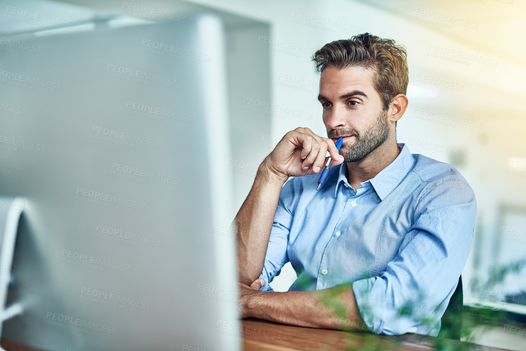 Buy stock photo Shot of a young businessman working on a computer in an office