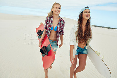 Buy stock photo Shot of two young friends sand boarding in the desert