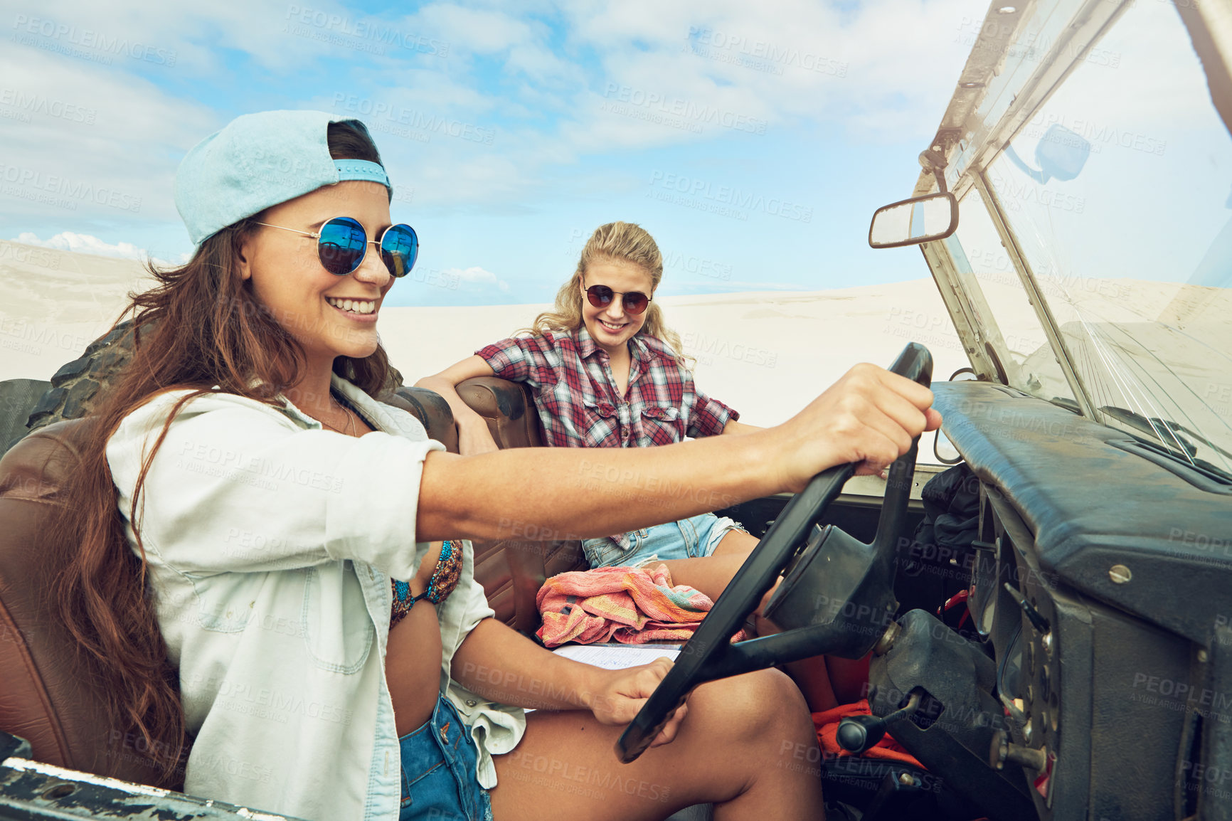 Buy stock photo Shot of two young friends going on a road trip in the desert