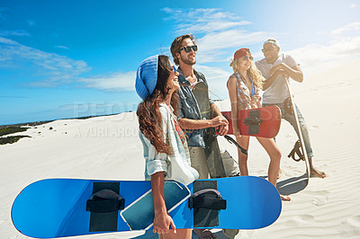 Buy stock photo Shot of a group of young friends sandboarding in the desert