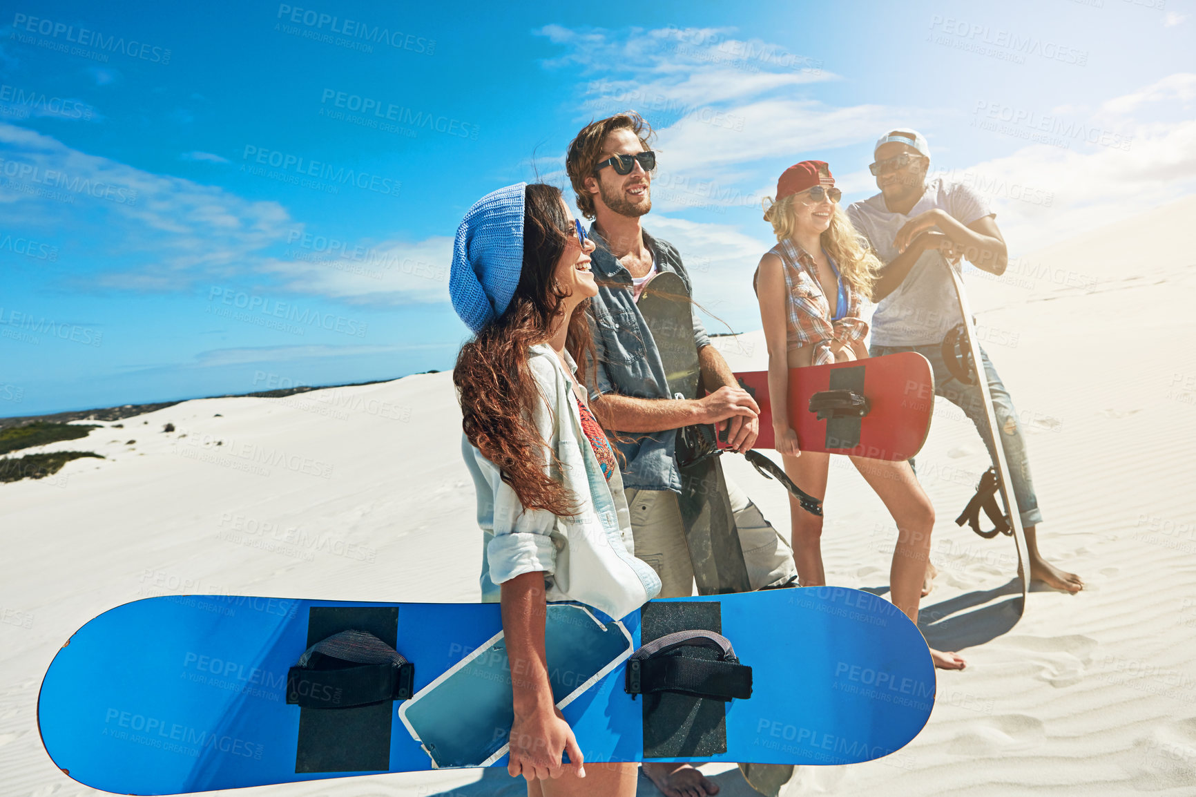 Buy stock photo Shot of a group of young friends sandboarding in the desert