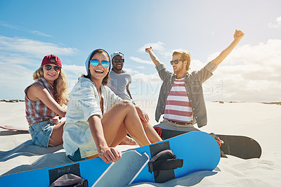 Buy stock photo Shot of a group of young friends sandboarding in the desert