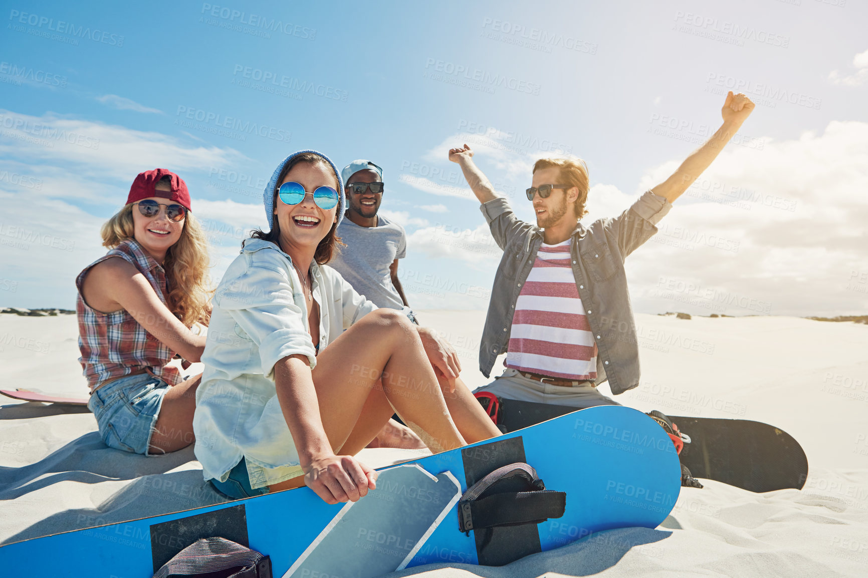 Buy stock photo Shot of a group of young friends sandboarding in the desert