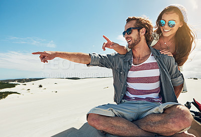 Buy stock photo Shot of a young couple sandboarding in the desert
