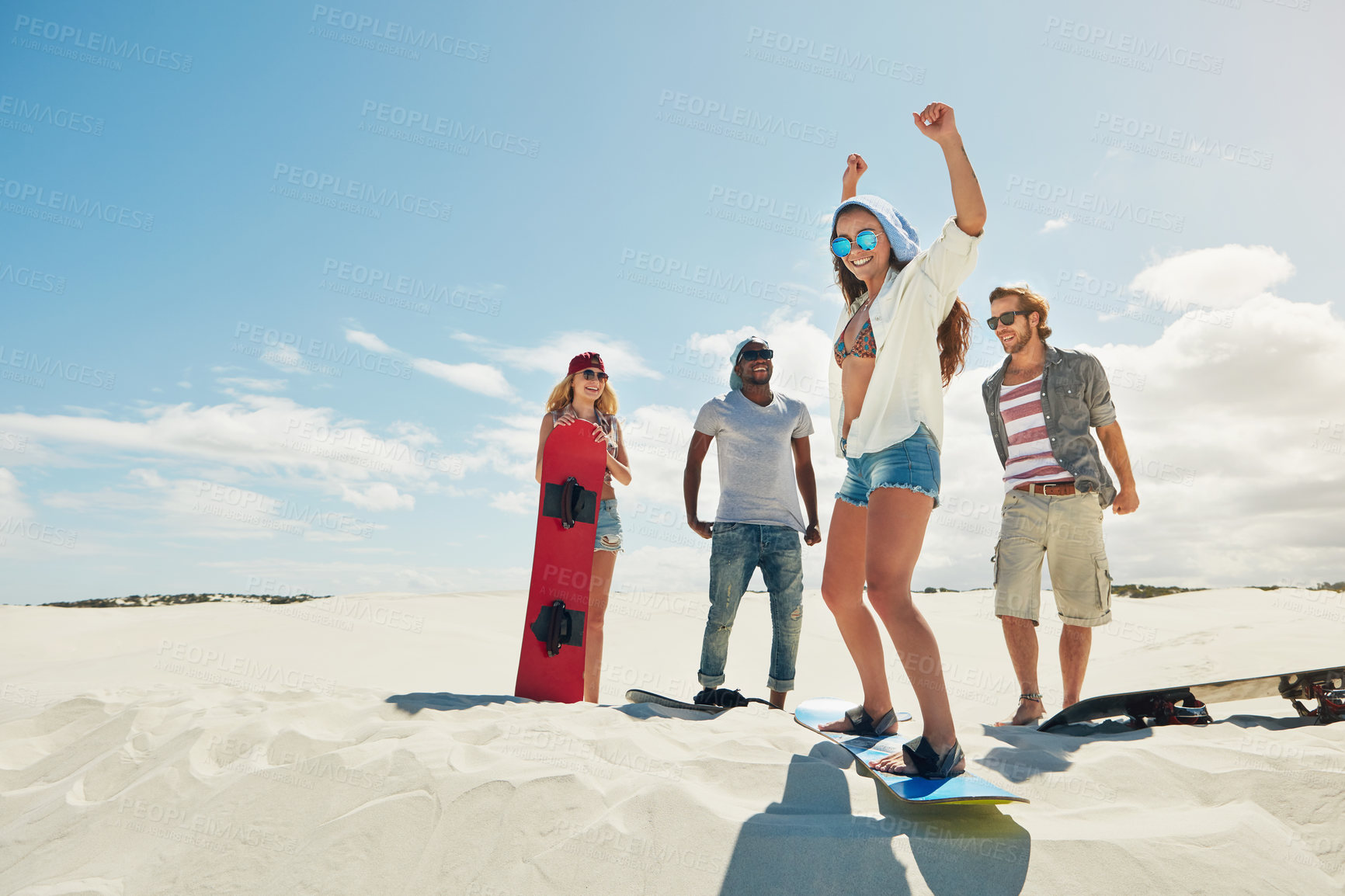 Buy stock photo Shot of a group of young friends sandboarding in the desert