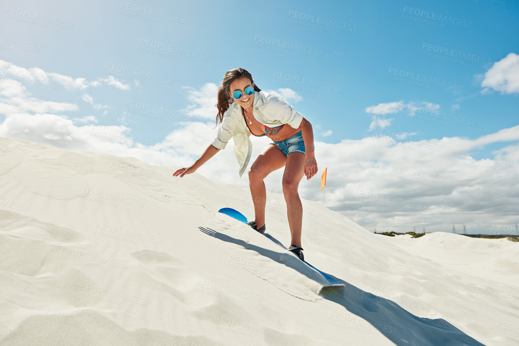 Buy stock photo Shot of a young woman sand boarding in the desert