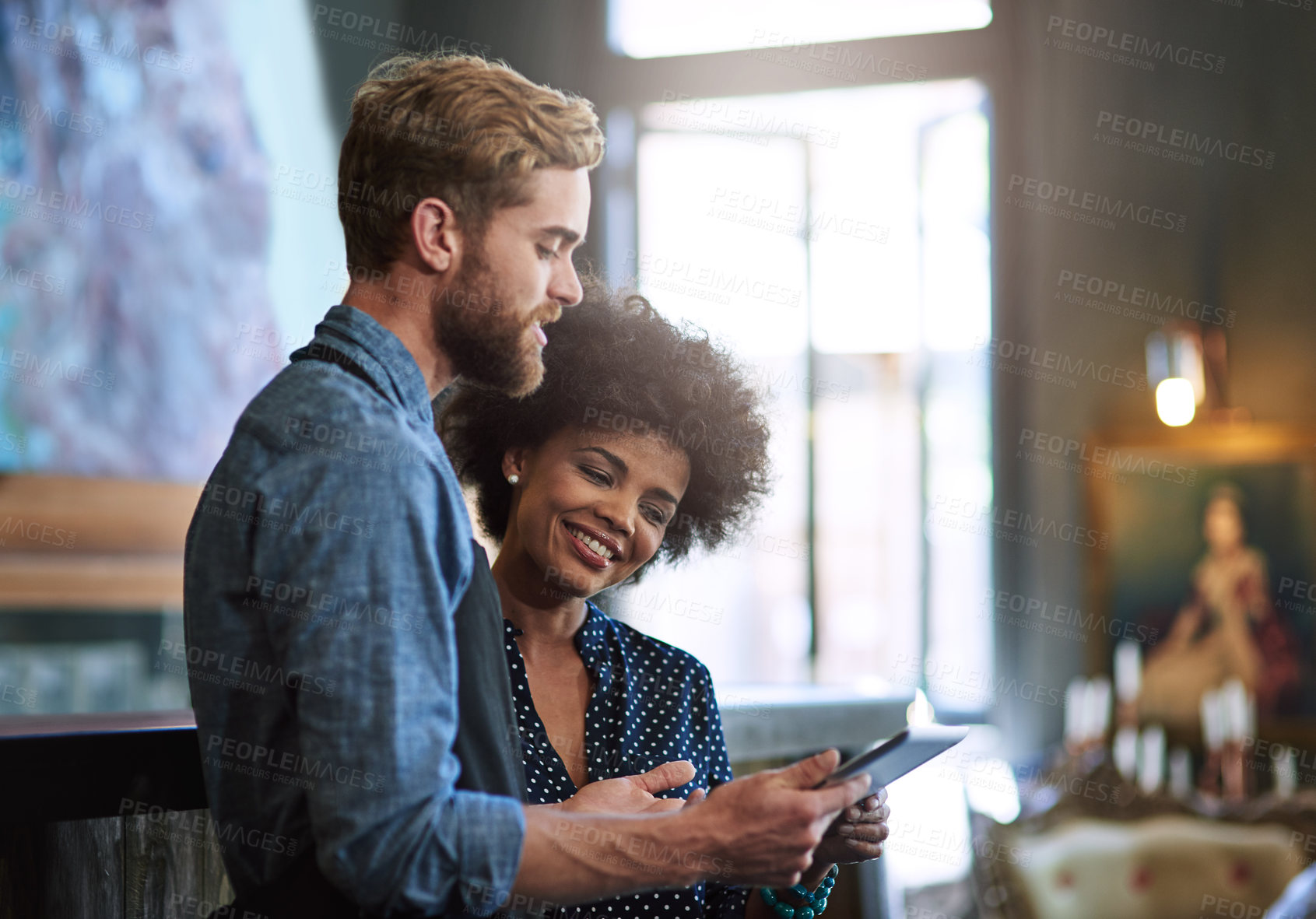 Buy stock photo Shot of two people using a digital tablet in a cafe