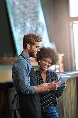 Buy stock photo Shot of two people using a digital tablet in a cafe