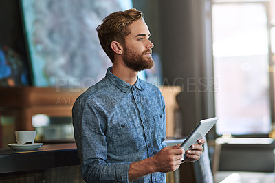 Buy stock photo Shot of a young man using a digital tablet in a cafe