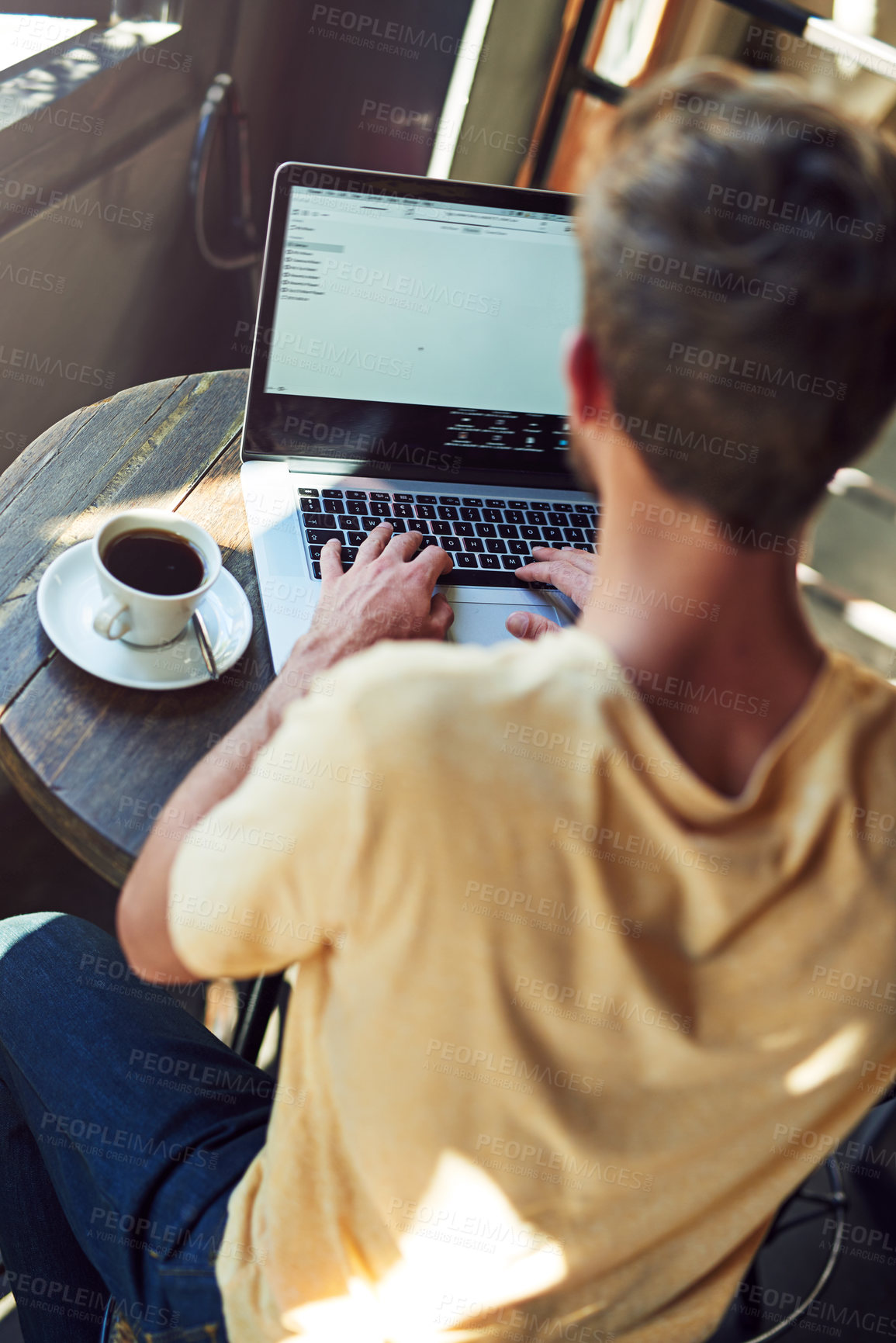 Buy stock photo Shot of a young man using a laptop in a cafe