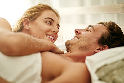 Buy stock photo Shot of an affectionate young couple relaxing in bed at home