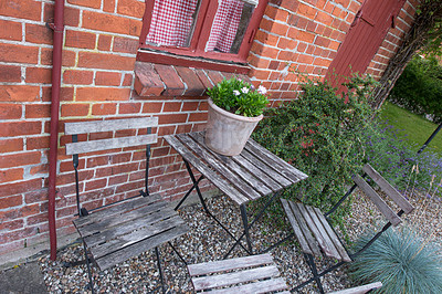 Buy stock photo Wooden courtyard chairs and table in a private home garden with a fresh green potted plant in Denmark. A serene, tranquil, peaceful backyard in Sweden. Relaxing in a secluded area in springtime