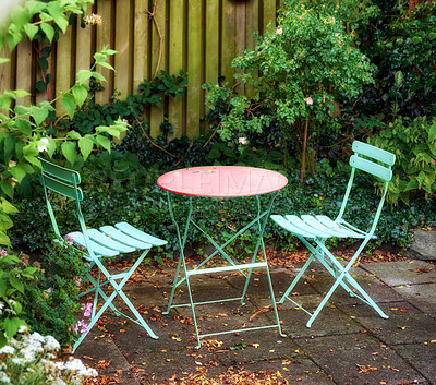 Buy stock photo Metal chairs and table with blossoming plants in a park or private courtyard outdoors. Tranquil lush green landscape and relaxing spot in a garden to enjoy cosy picnic or quiet afternoon in spring