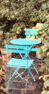 Buy stock photo Two courtyard chairs and a blue metal table in a peaceful private home garden with green plants. Comfortable outdoor patio furniture set and seating in an empty, tranquil backyard with fresh flowers