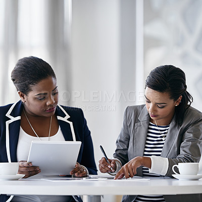 Buy stock photo Shot of two colleagues working together while sitting at a desk in an office