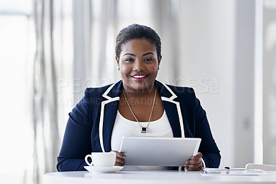 Buy stock photo Portrait of a young businesswoman using a digital tablet while sitting at a desk in an office