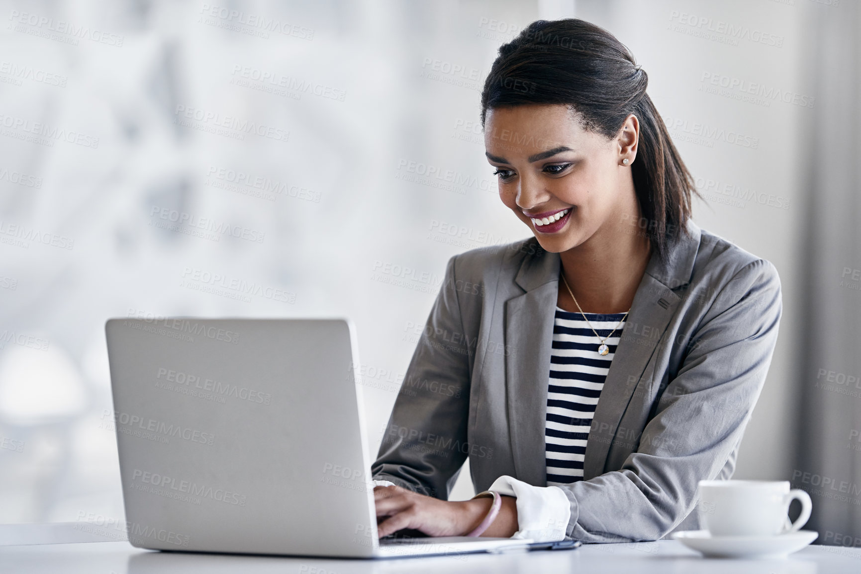 Buy stock photo Shot of a young businesswoman using a laptop while sitting at a desk in an office