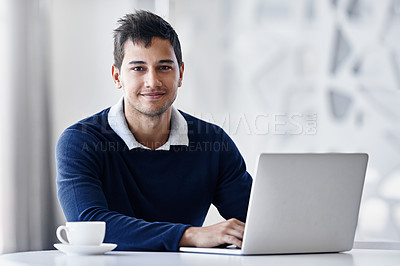 Buy stock photo Portrait of a young businessman using a laptop while sitting at a desk in an office