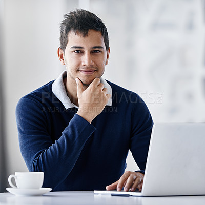 Buy stock photo Portrait of a young businessman using a laptop while sitting at a desk in an office