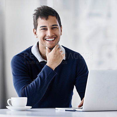 Buy stock photo Portrait of a smiling young businessman using a laptop while sitting at a desk in an office