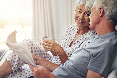 Buy stock photo Coffee, newspaper and a senior couple in the bedroom, enjoying retirement in their home in the morning. Tea, reading or love with a happy mature man and woman in bed together to relax while bonding