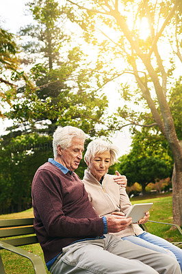 Buy stock photo Shot of a senior couple using a digital tablet together in the park