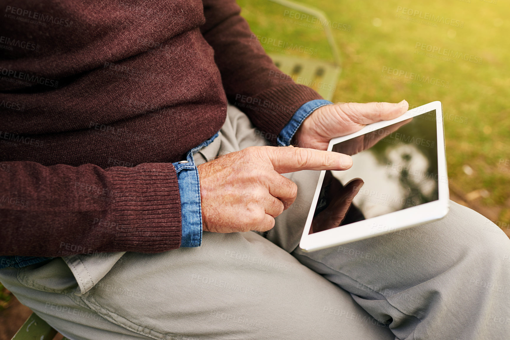 Buy stock photo Closeup shot of a man using a digital tablet in the park