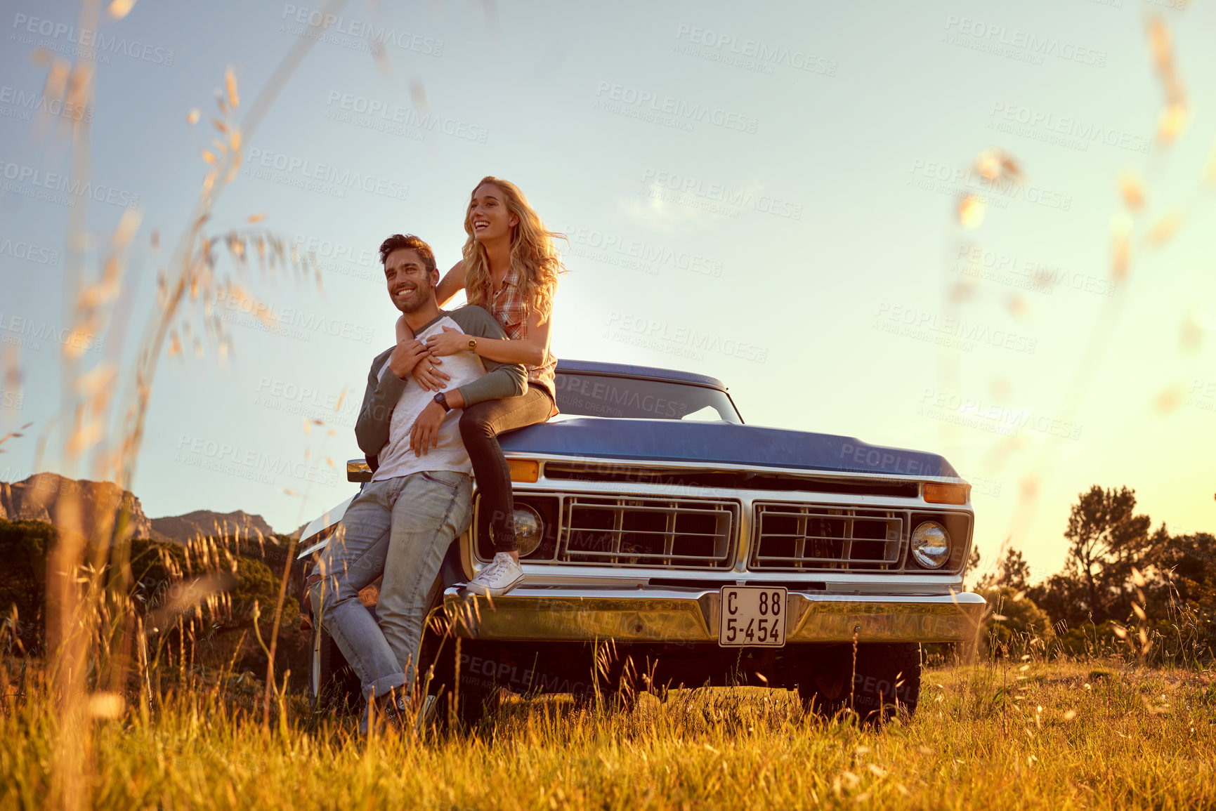 Buy stock photo Happy, travel and couple by car in field for road trip break, holiday adventure or romance with nature view. Fun journey, people and hug by truck in countryside with bonding, sightseeing or exploring