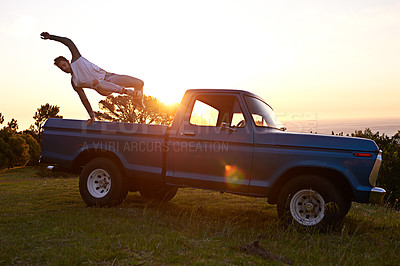 Buy stock photo Shot of a young man jumping out the trunk of his truck on a roadtrip