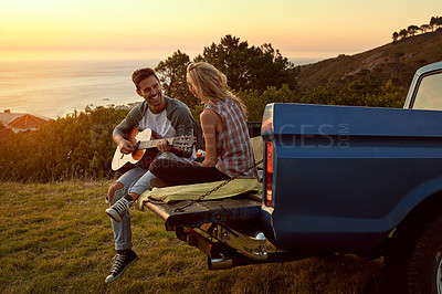 Buy stock photo Guitar, truck and couple playing music in nature by sunset on date for romantic getaway roadtrip. Happy, outdoor and man serenading woman with string instrument in field for vacation or holiday.