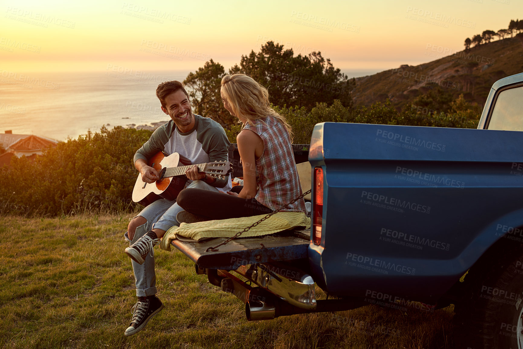 Buy stock photo Guitar, truck and couple playing music in nature by sunset on date for romantic getaway roadtrip. Happy, outdoor and man serenading woman with string instrument in field for vacation or holiday.