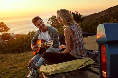 Buy stock photo Shot of a young man playing guitar for his girlfriend on a roadtrip
