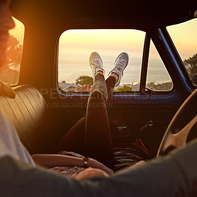 Buy stock photo Shot of a young woman relaxing on her boyfriend’s lap with her feet up during a road trip