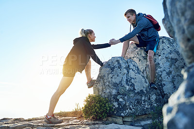 Buy stock photo Full length shot of a young man helping his girlfriend while hiking