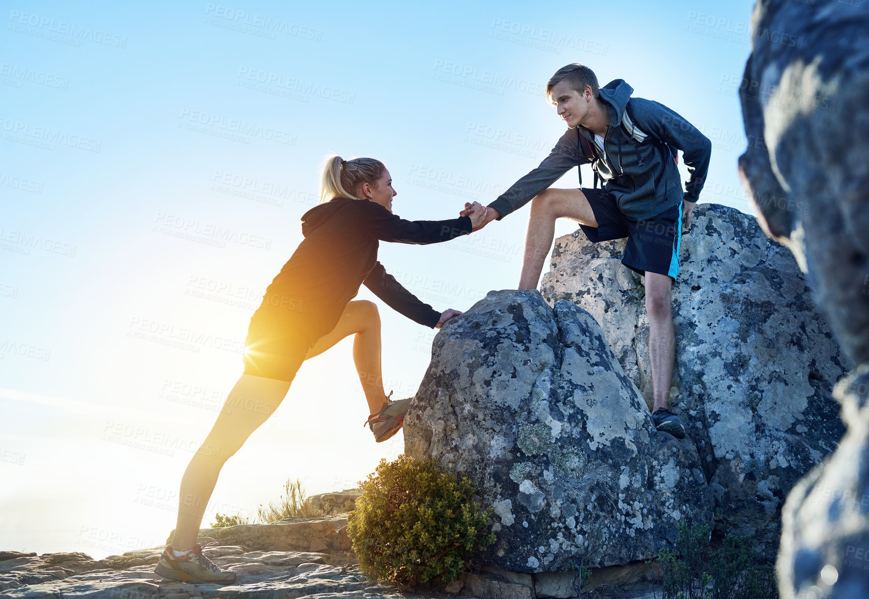 Buy stock photo Full length shot of a young man helping his girlfriend while hiking