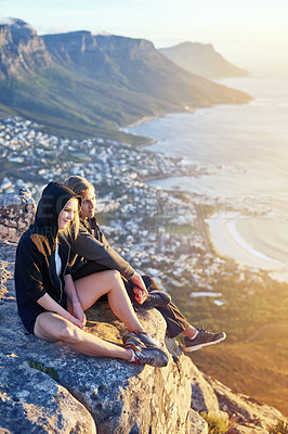 Buy stock photo Full length shot of a young couple sitting on a mountain top