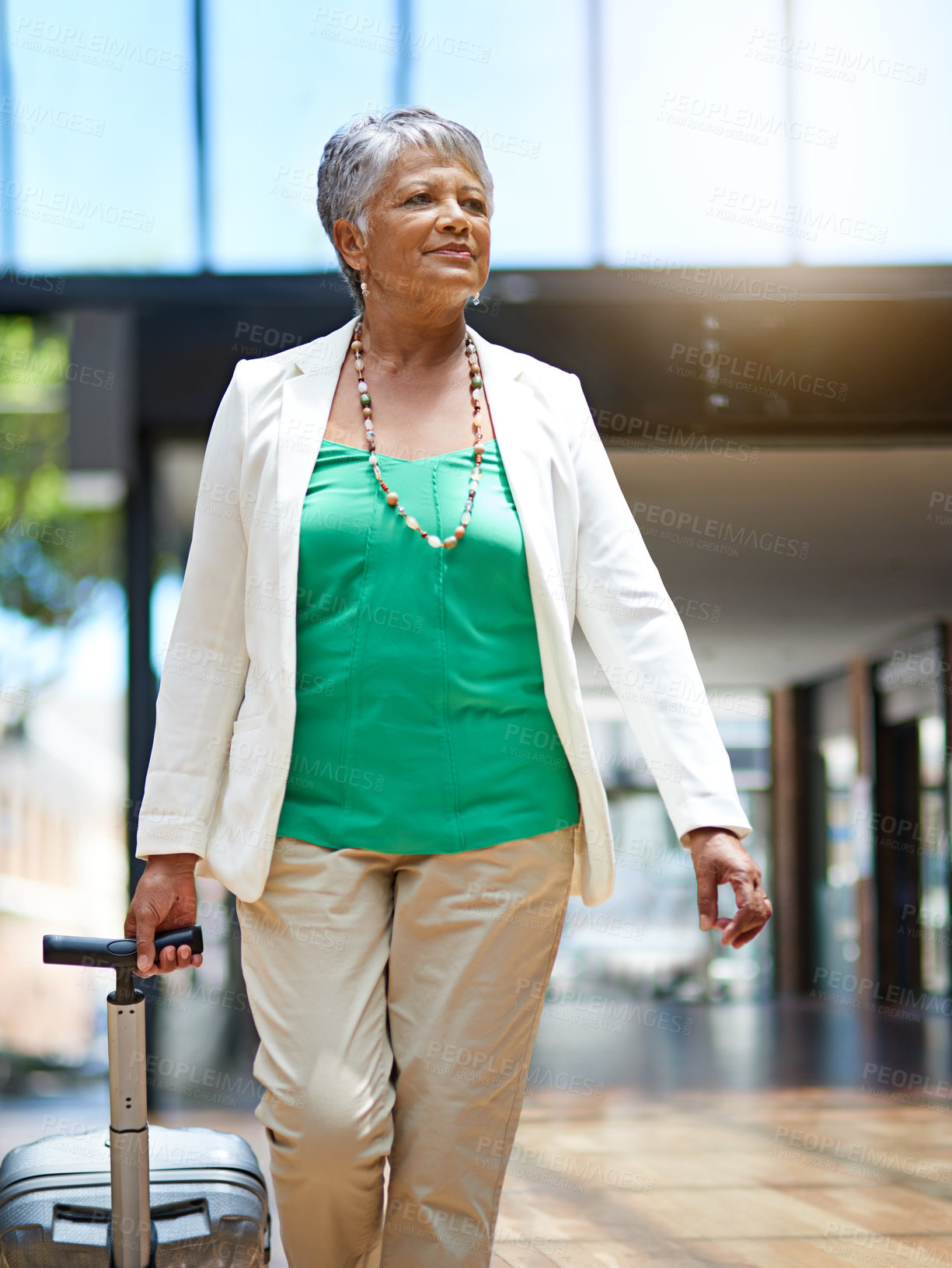 Buy stock photo Shot of a mature woman walking in an airport terminal with her suitcase